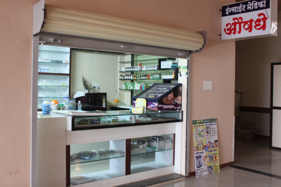 Insight Medico in-house pharmacy at Insight Institute with a glass display counter, back-shelf medication racks and a bilingual signboard above